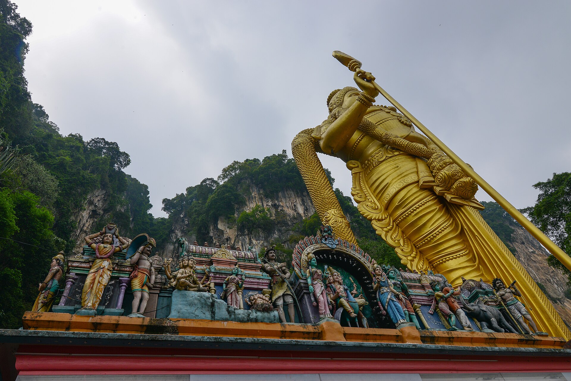 The golden Murugan statue and the temple sculptures at Batu Caves, the limestone hill behind