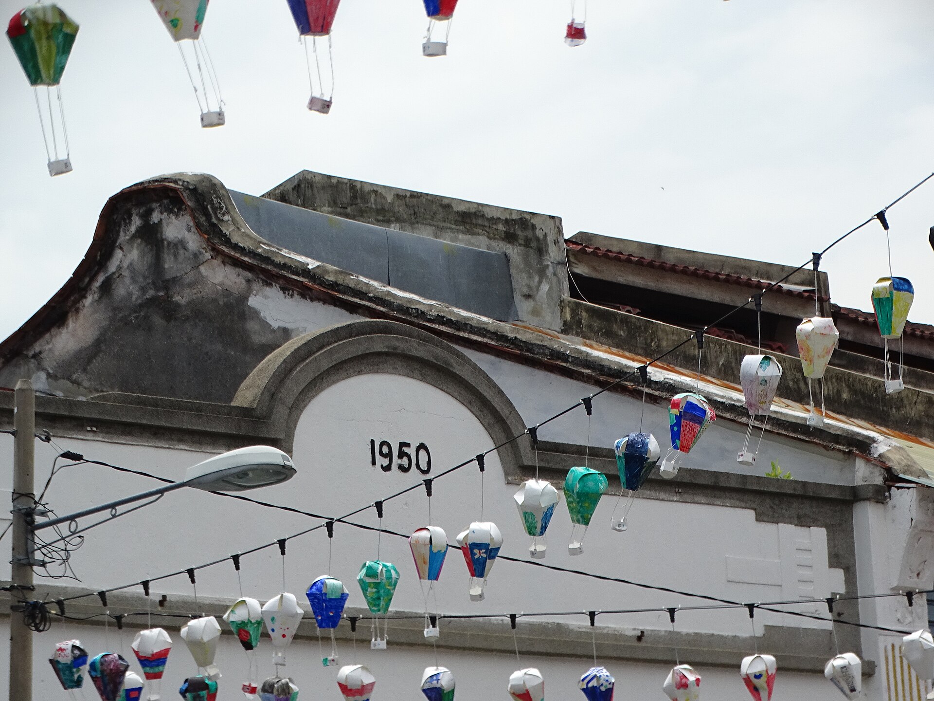 Paper lanterns strung across Armenian Street in George Town, under a 1950 shophouse gable
