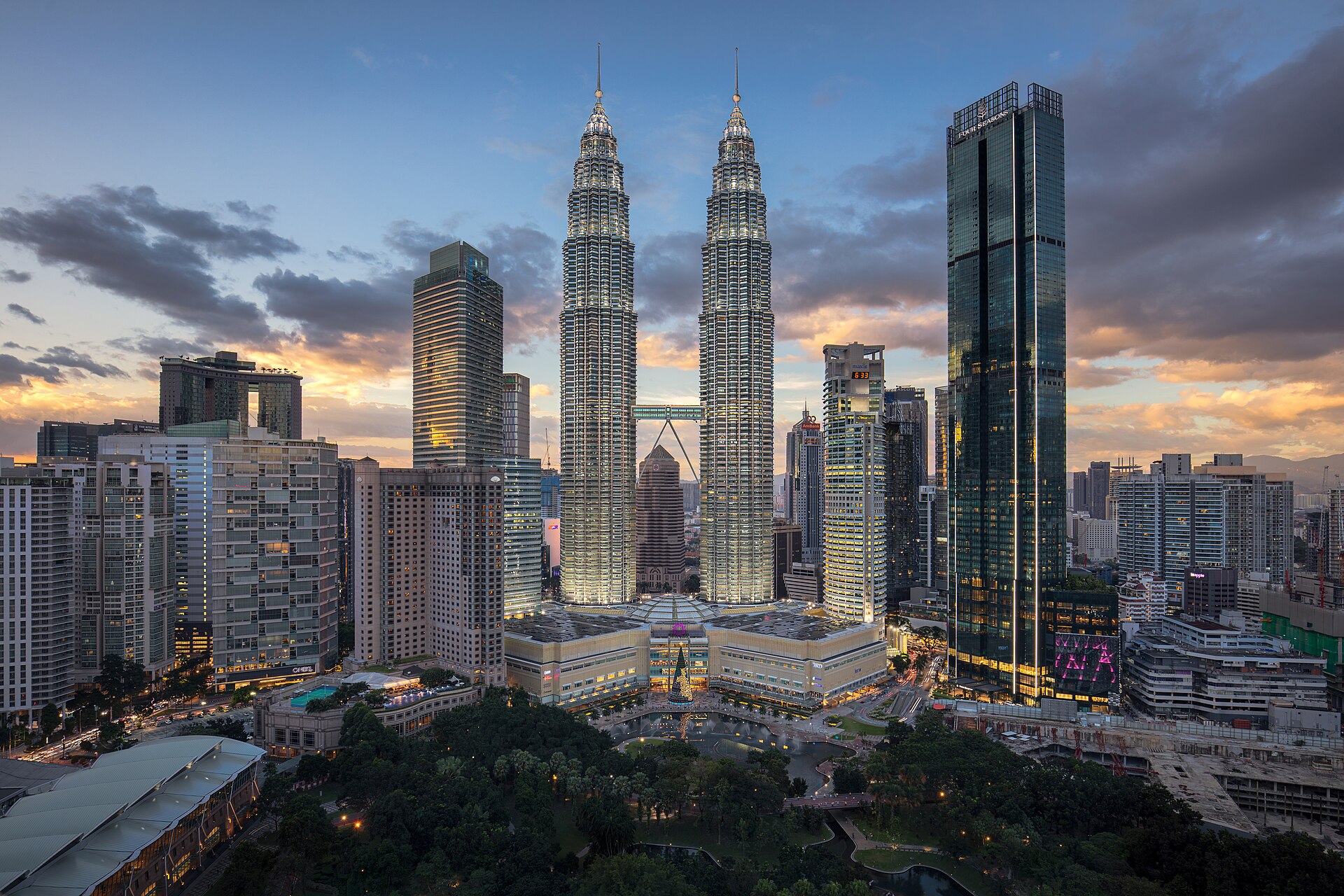 The Petronas Twin Towers above KLCC Park and the lake at dusk, the Kuala Lumpur skyline around them